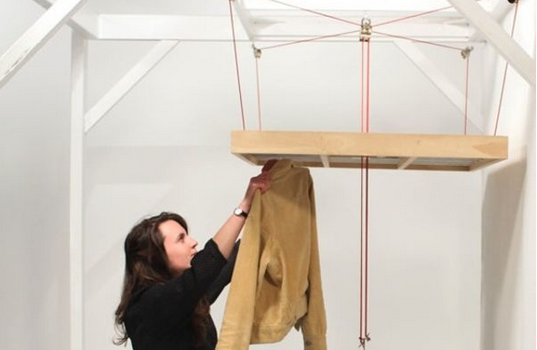 Un système de suspensions permet de relever cette table pour utiliser les accroches sous celle-ci et suspendre son linge.
